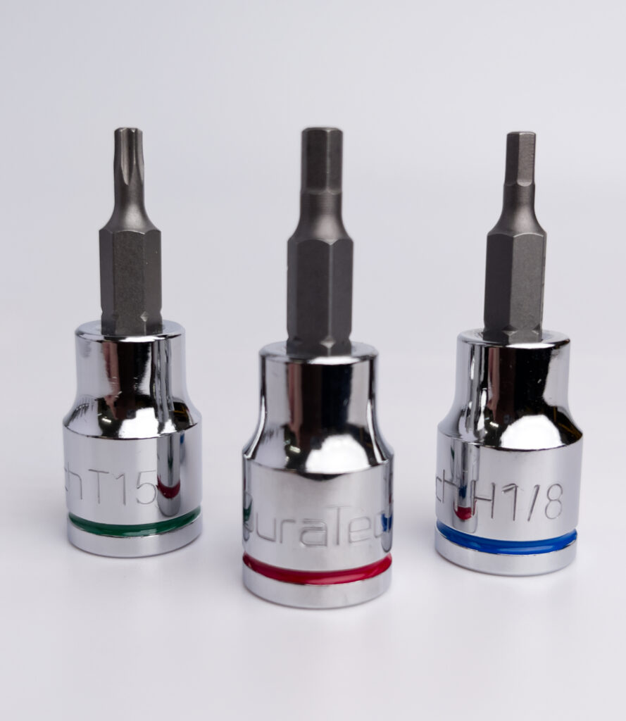 Close-up of three chrome socket bits with hex and Torx heads, labeled H1/8, Duratech, and T15, color-coded with blue, red, and green rings, displayed on a white background for a ToolVerdict tool review.