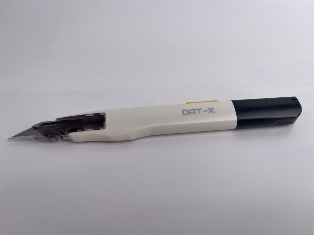 Side profile of the DAT-X utility knife with the blade extended, showing ergonomic design and modern color scheme.
