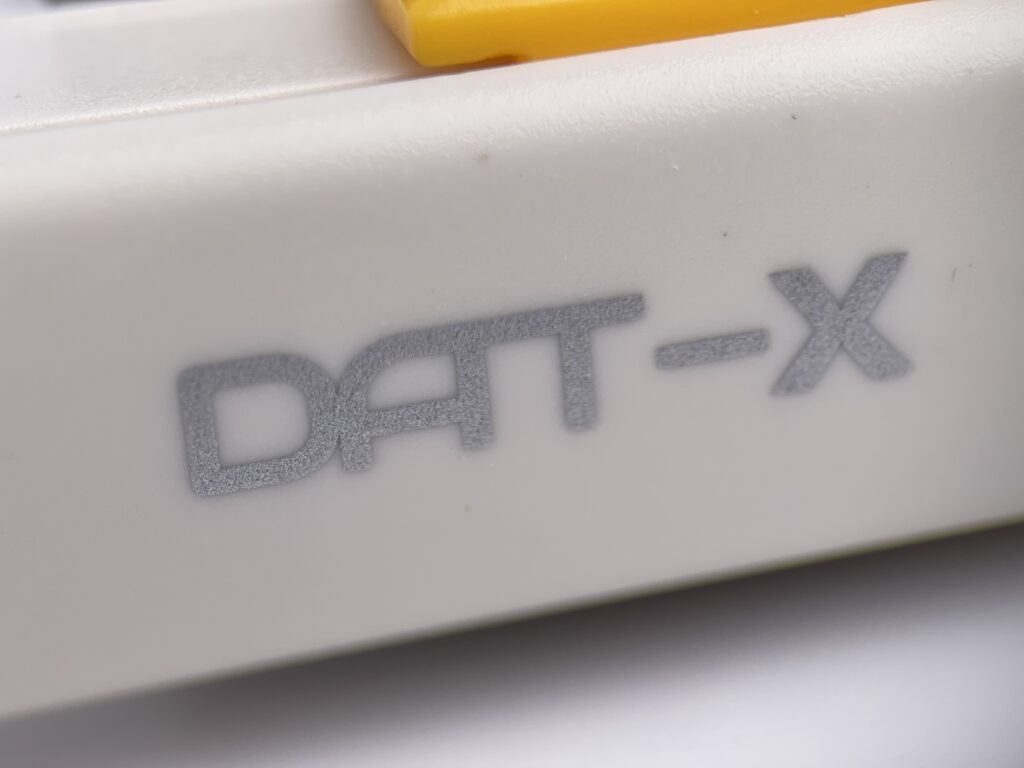 Macro close-up of the DAT-X logo printed on the body of a precision utility knife, showing fine surface texture and detail.