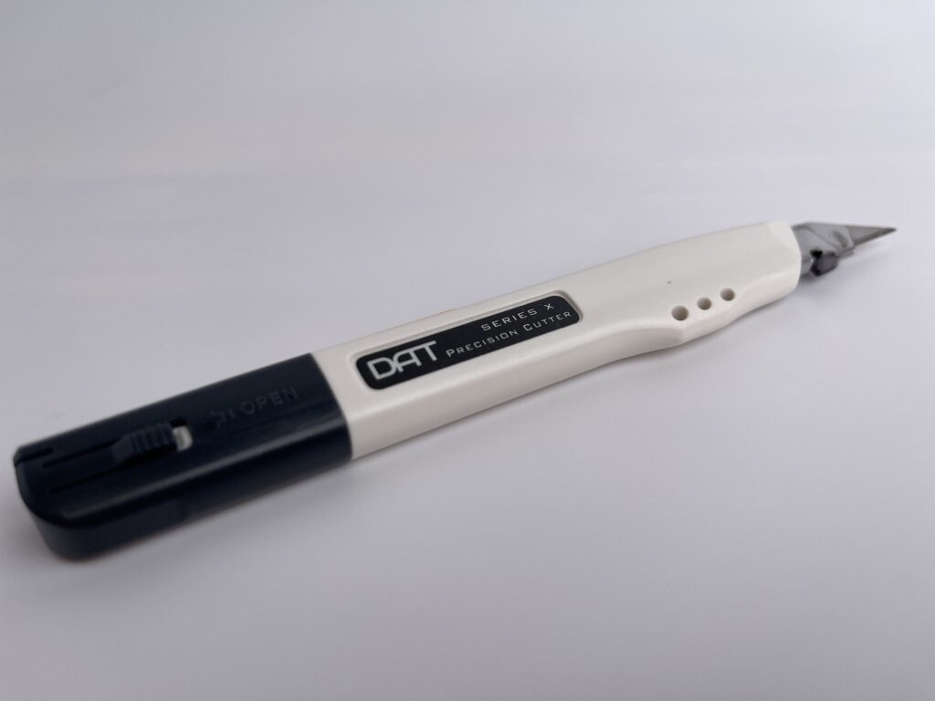Side view of the DAT Series X precision utility knife with dark blue and white handle, labeled as a precision cutter.