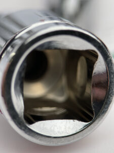 Macro view inside the square drive end of a chrome socket, showcasing polished interior walls and connection detail.